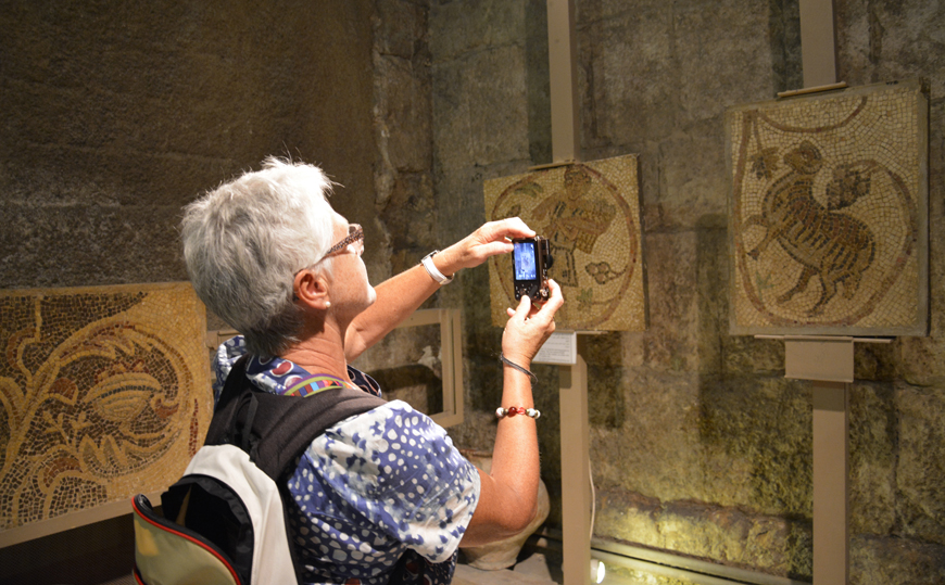 A tourist takes a photo of mosaics on display at the Roman Theatre museum in downtown Amman recently (Photo by Amjad Ghsoun)